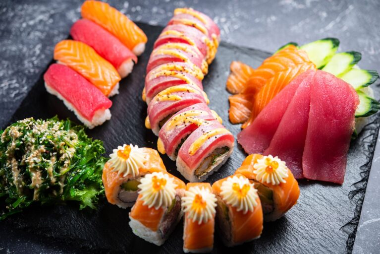 Sushi platter on dark slate, professional food photography, dark moody lighting, deep shadows